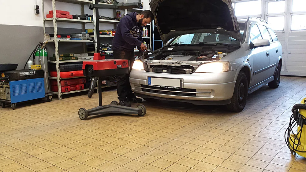 Mechaniker arbeitet an einem Opel Astra mit geöffneter Motorhaube